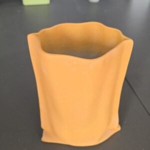 Mustardo - porcelain vase ceramic shaped like a crumpled paper bag, in a mustard-orange shade.